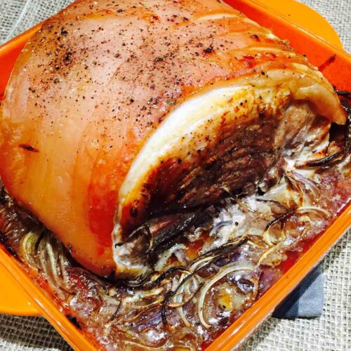 A chunky piece of roast pork, on a bed of beer and onions.