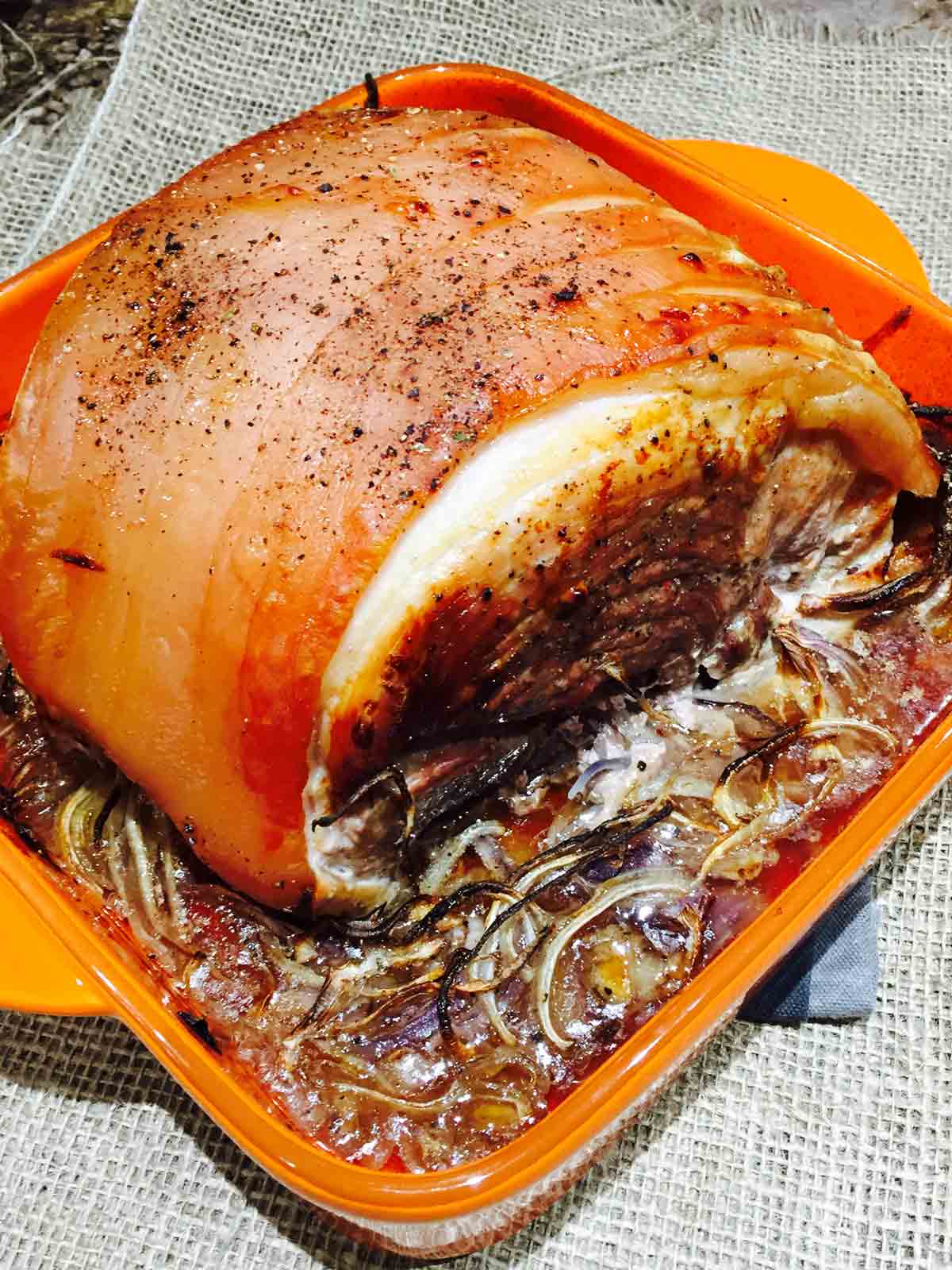 A chunky piece of roast pork, on a bed of beer and onions.