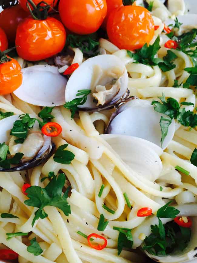 A close-up of the seafood linguini pasta with cherry tomatoes and parsley sprinkled over.