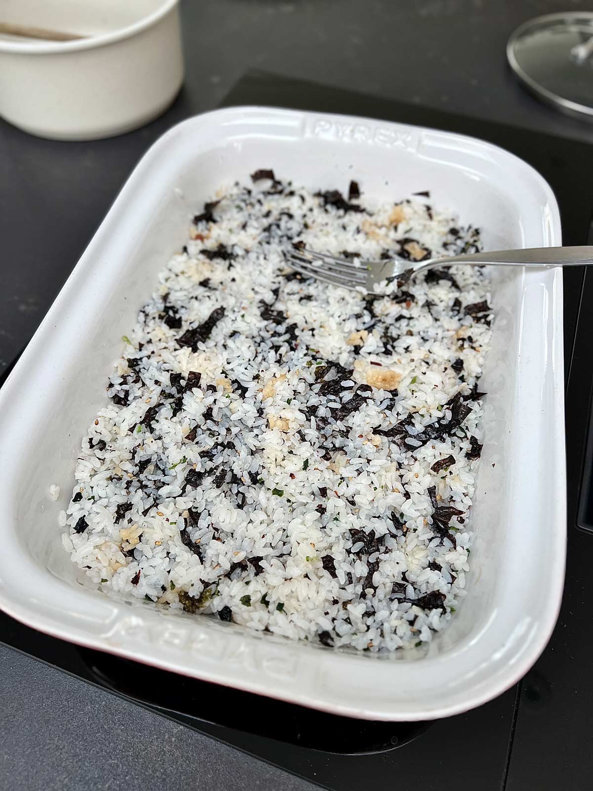 One layer of seasoned sushi rice layered in a white rectangular oven dish.