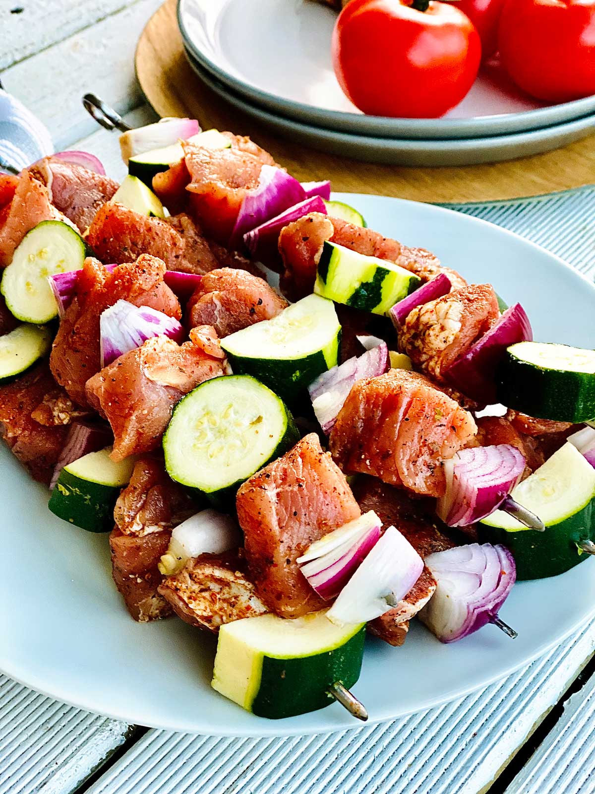 Skewered chicken meat on a white plate, ready to get into the oven