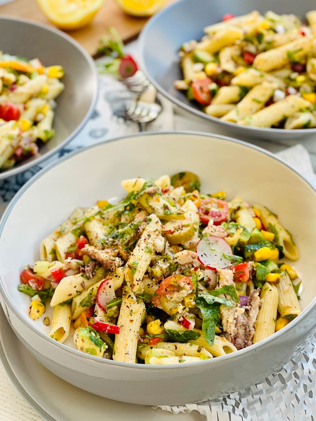 A closeup of a bowl containing spanish sardines pasta penne with sweet corn, radish black pepper and herbs