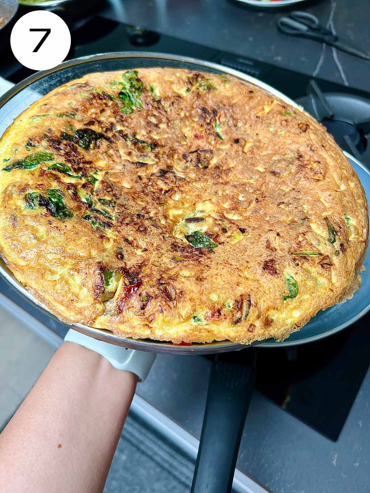 Spinach and feta omelette being flipped on a lid.