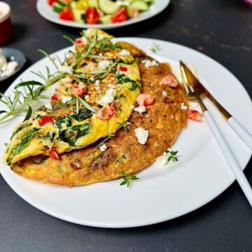 Feta and spinach omelette on a white plate herbs sprinkled.