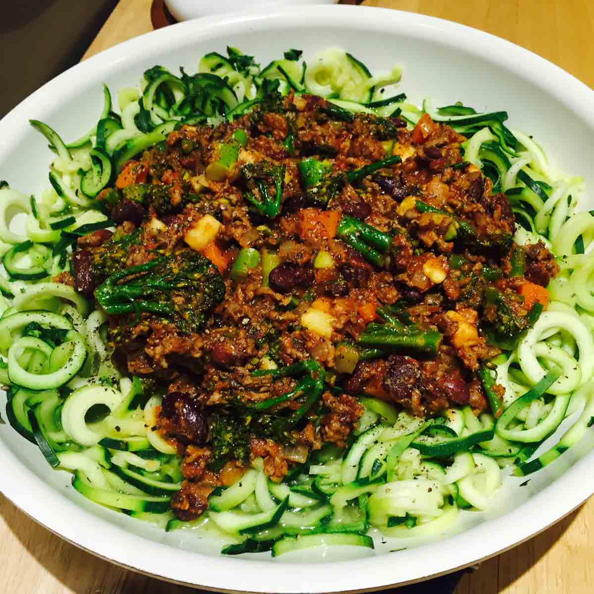 Spiralized zucchini pasta, in a white bowl, with sauce