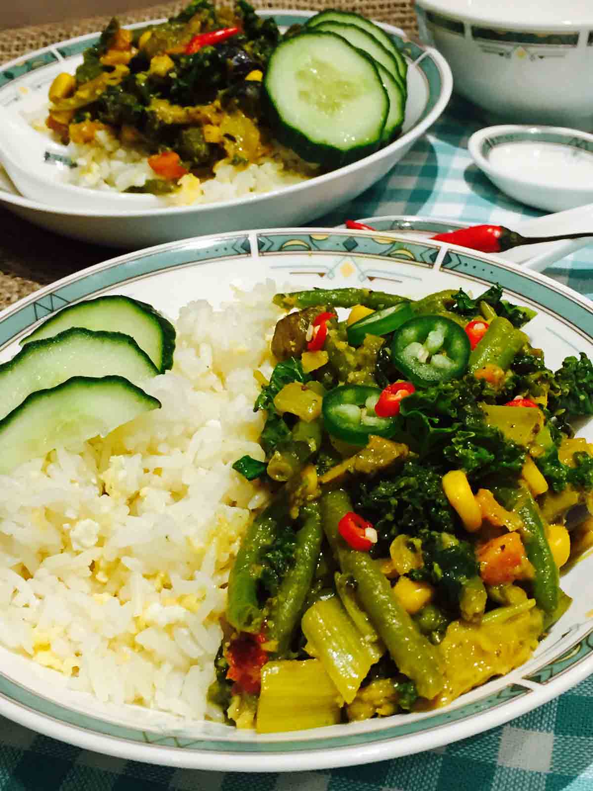 A white plate of scrumptious vegetarian Thai curry, together with egg-fried rice and other veggies.