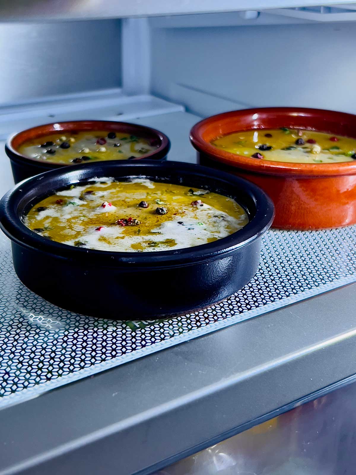 Three ramekins containing chicken liver pate in refrigerator cooling away.