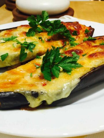Two Tomato & cheese topped aubergines, on a white plate