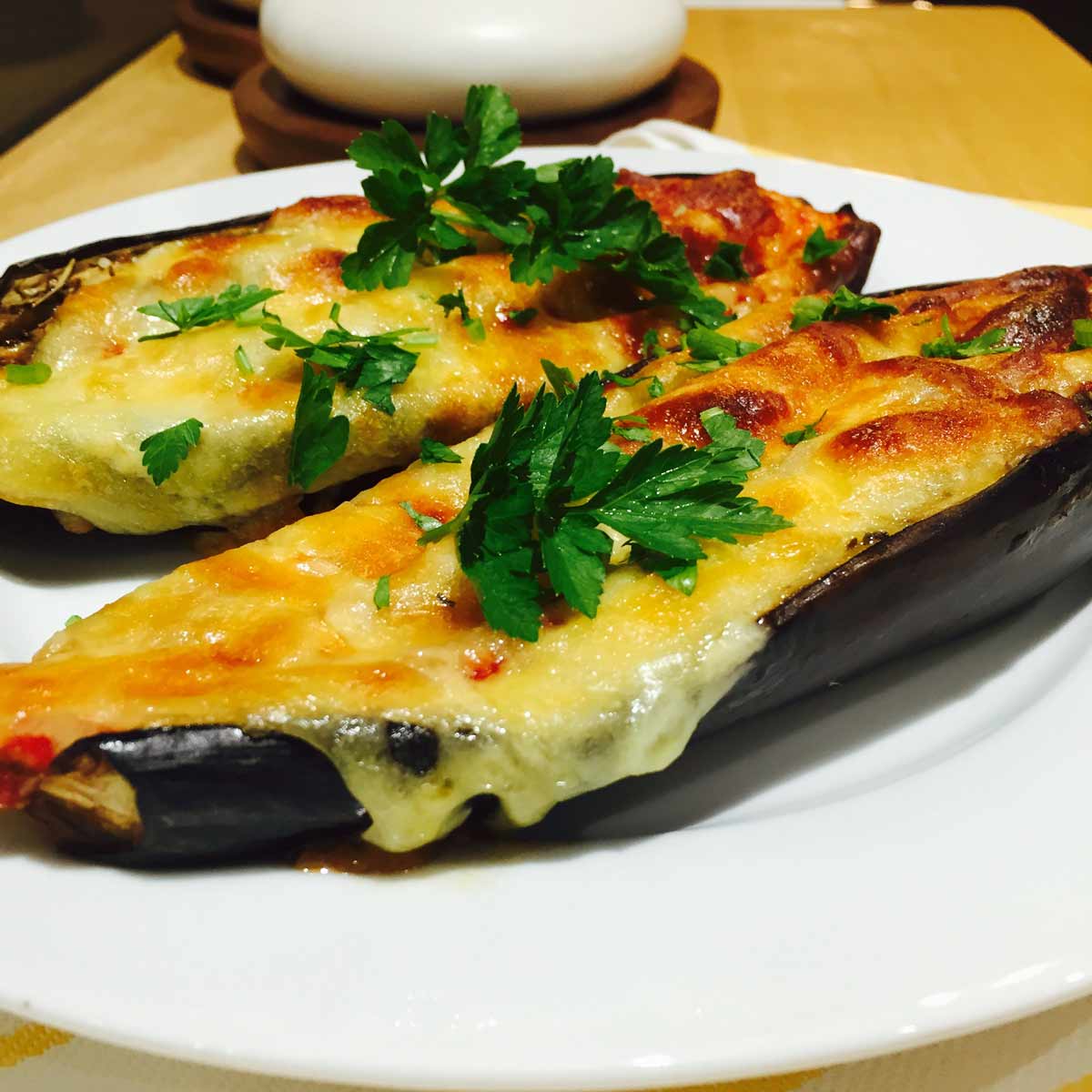 Two Tomato & cheese topped aubergines, on a white plate