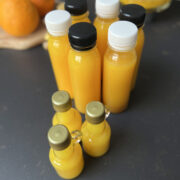 Ginger, lemon, turmeric drink shots. Six bottles with black and white caps.