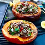 Two kabucha stuffed squash halves on a griddle plate